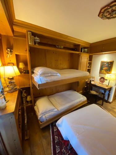 a room with three bunk beds and a lamp at Incantevole monolocale in centro a Cortina. in Cortina dʼAmpezzo