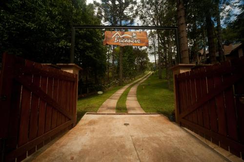 an entrance to a driveway with a sign on a fence at Pousada Bucaneve in Monte Verde