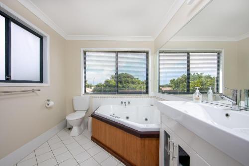 a bathroom with a tub and a sink and a toilet at Oceania Peace in Yamba
