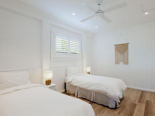a white bedroom with two beds and a window at 81 Horace St WI FI and air conditioning in Shoal Bay