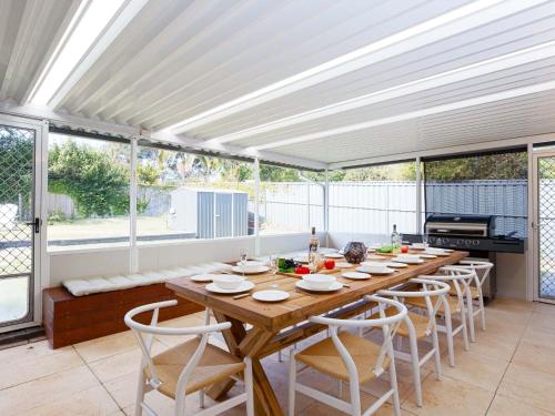 a dining room with a long wooden table and chairs at 81 Horace St - Wifi, Pool and air conditioning in Shoal Bay