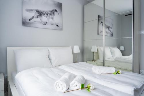 a bedroom with a white bed with towels and a mirror at Apartament na Wzgórzu 4 Sauny, ebike, las, widok - 5D Apartamenty in Świeradów-Zdrój