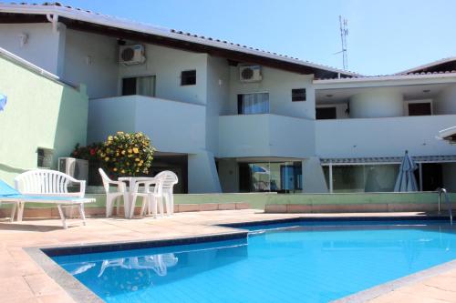 a swimming pool with two chairs and a building at Hotel Ponta de Areia in Porto Seguro