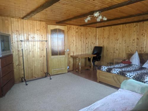 a bedroom with a bed and a desk and a table at Приват-котедж Зарінок in Mykulychyn