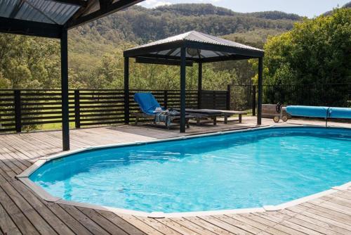 a swimming pool on a wooden deck with a gazebo at Clerevale Vacation Home in Kangaroo Valley