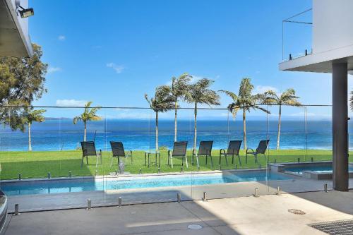 a swimming pool with chairs and the ocean in the background at Lakes Resort in Toukley