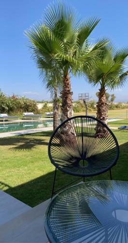 a metal bench with palm trees in a park at Villa luxueuse avec piscine in Marrakesh