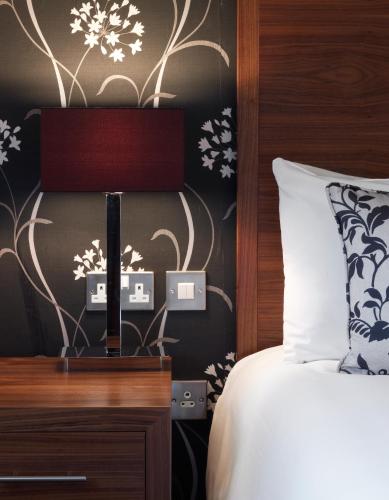 a bedroom with a bed and a wall with flowers at The Boleyn Hotel in Staines