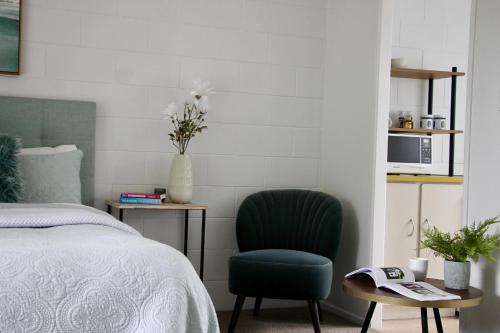 a bedroom with a green chair next to a bed at Oceans 88 Whitianga Coastal Suites in Whitianga