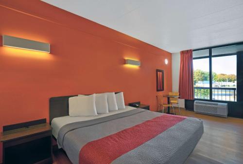 a hotel room with a bed with an orange wall at Motel 6-Seaford, DE in Seaford