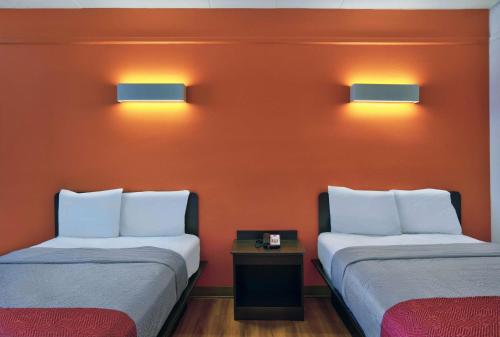 two beds in a room with orange walls and lights at Motel 6-Seaford, DE in Seaford