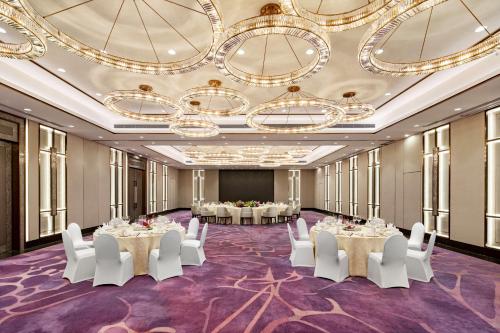 a ballroom with tables and white chairs and a stage at Radisson Collection Hotel, Xing Guo Shanghai in Shanghai