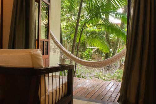 a room with a hammock on a porch with trees at Pousada Villa Bella in Itacaré