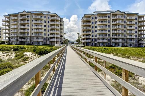 a boardwalk over the beach with two apartment buildings at Ocean Place in Fernandina Beach