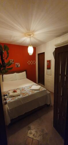 a bedroom with a bed and a red wall at Pousada Farol do Patacho in Pôrto de Pedras