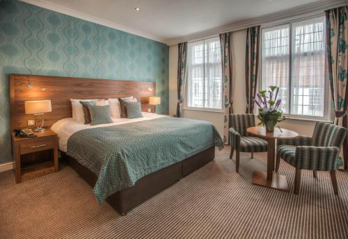 um quarto de hotel com uma cama, uma mesa e cadeiras em The Boleyn Hotel em Staines