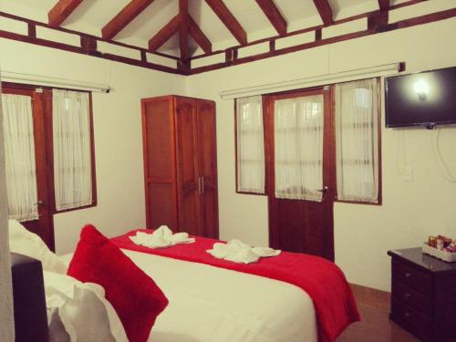 a bedroom with a bed with a red blanket at Hospederia Sandaned in Villa de Leyva