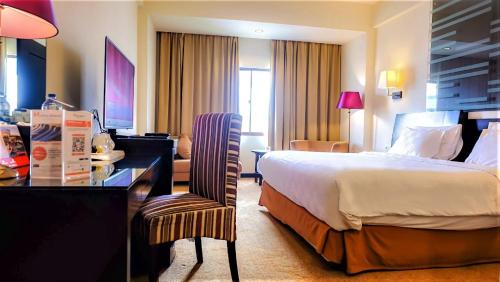 a hotel room with a bed and a desk at Swiss-Belhotel Silae Palu in Palu