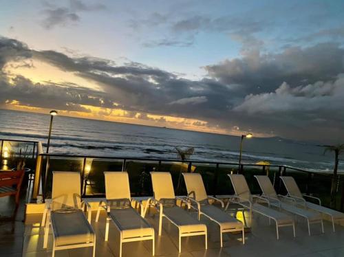 a group of chairs and tables on a balcony with the ocean at Pé na areia - próximo ao Beto Carreiro in Barra Velha