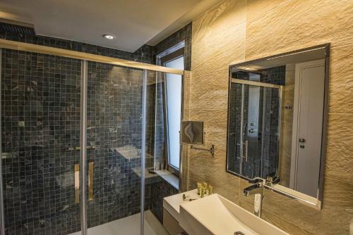 a bathroom with a shower and a sink and a mirror at Swell Boutique Hotel in Rethymno Town