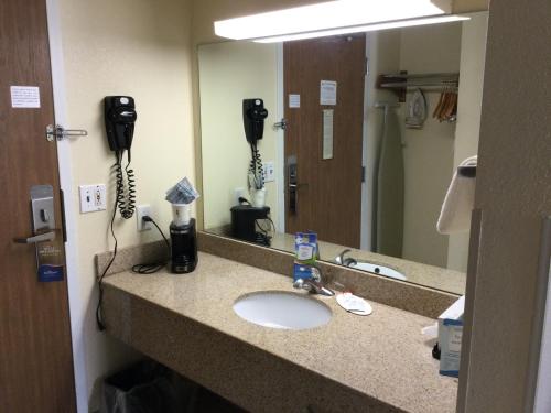 a bathroom counter with a sink and a mirror at Baymont by Wyndham Janesville in Janesville