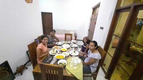 a group of people sitting around a table with food at Ever Green Villa in Negombo