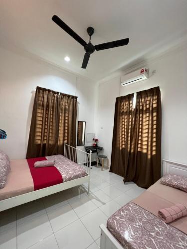 a bedroom with two beds and a ceiling fan at AmVilla in Kota Bharu