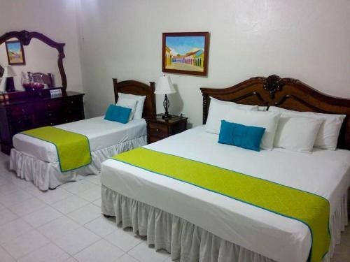 1 Schlafzimmer mit 2 Betten und grüner und weißer Bettwäsche in der Unterkunft Hotel Casa Blanca by Rotamundos in Tlacotalpan