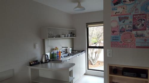 a white kitchen with a counter and a window at Akaroa Waterfront Motels in Akaroa