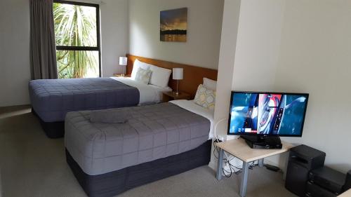 a hotel room with two beds and a flat screen tv at Akaroa Waterfront Motels in Akaroa