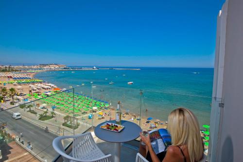 a woman sitting at a table looking at the beach at Swell Boutique Hotel in Rethymno Town