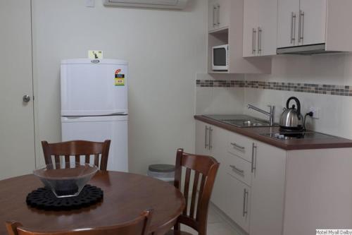 a kitchen with a table and a white refrigerator at Motel Myall in Dalby