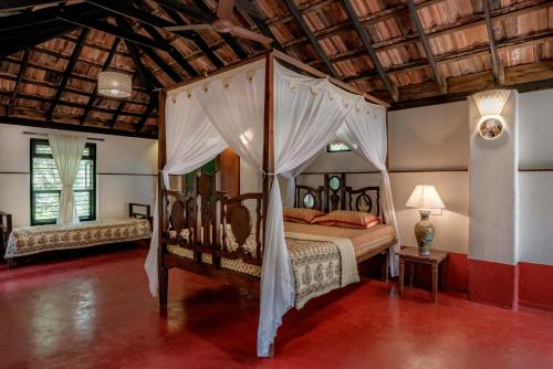 a bedroom with a canopy bed in a room at SaffronStays Suvarna Sangam, Udupi in Udupi