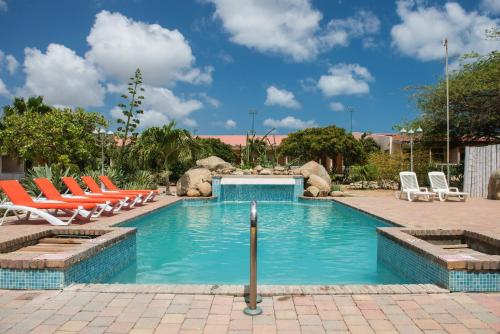 a swimming pool with lounge chairs in a resort at Camacuri Apartments in Oranjestad