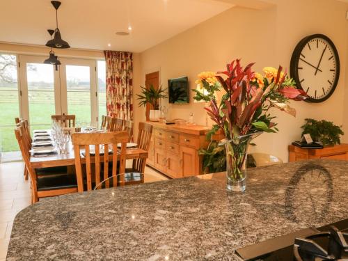 uma cozinha e sala de jantar com uma mesa com um vaso de flores em Anneside em Carnforth