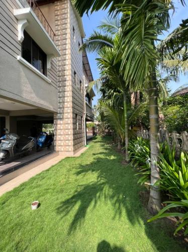 a yard with palm trees in front of a house at Neville's Villa - Pet friendly with Pool in Alibaug