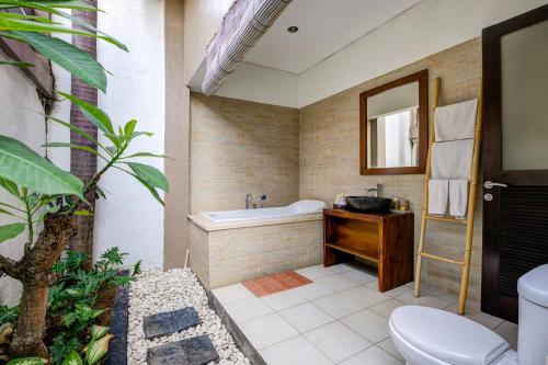 a bathroom with a tub and a toilet and a sink at Villa Raka Managed by Manara in Legian