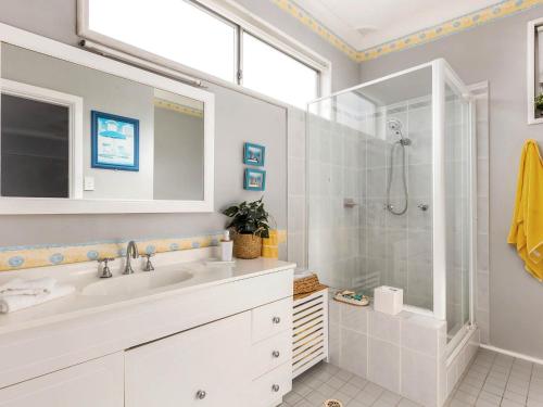 a white bathroom with a shower and a sink at Wataview in Gerroa