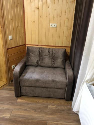 a grey couch sitting in a room with wooden floors at Байка Карпат in Vorokhta