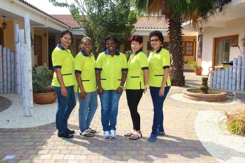 a group of women in yellow shirts standing in front of a house at Camacuri Apartments in Oranjestad