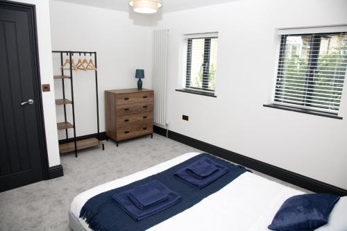 a bedroom with a bed and a dresser and windows at Little Elm - luxury home from home, free parking, 30-40 mins walk from Bath city centre in Bath