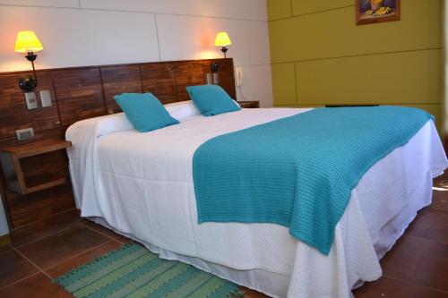 a bedroom with a large white bed with blue pillows at Hotel Cumbres de Atacama in Copiapó