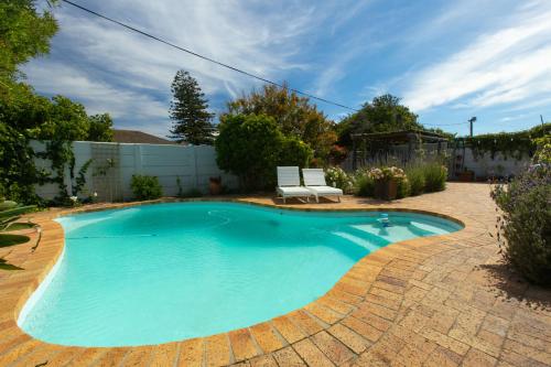 una piscina con una sedia in cortile di Surf Way Beach cottage a Città del Capo