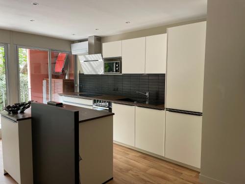 une cuisine avec des armoires blanches et un comptoir noir dans l'établissement T3 Arcachon centre proche plage, à Arcachon