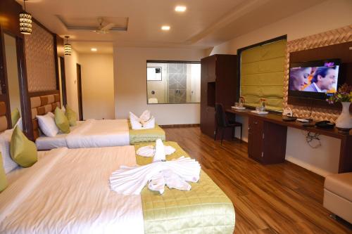 a hotel room with two beds and a flat screen tv at Khushi Riverside Resort & Spa in Mahabaleshwar