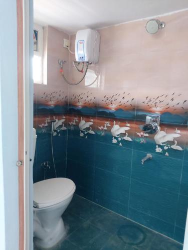 a bathroom with a toilet and a wall with birds on it at FEEL LIKE HOME near Cricket stadium in Visakhapatnam