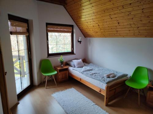 a bedroom with a bed and two green chairs at Balaton Garden in Balatongyörök