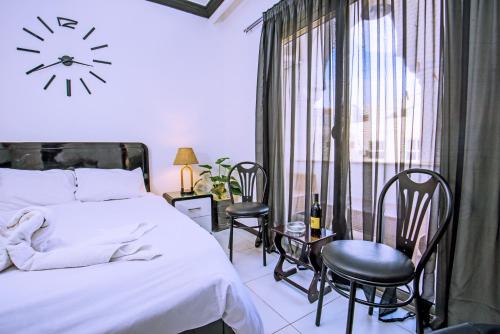 um quarto com uma cama e cadeiras e um relógio na parede em Rare 2BD Marina Hotspot With Pool, Fast Free WIFI & Balcony - 2 Kitchens & 2 Bathrooms - Western Standards - Sheraton Plaza 414-415 em Hurghada