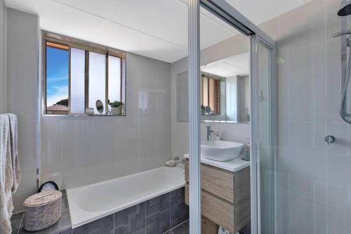 a white bathroom with a sink and a shower at Spacious 2BR near The Entrance Beach - 7Min Walk! in The Entrance