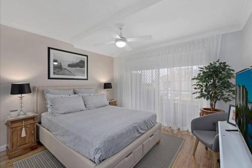a white bedroom with a bed and a window at Spacious 2BR near The Entrance Beach - 7Min Walk! in The Entrance